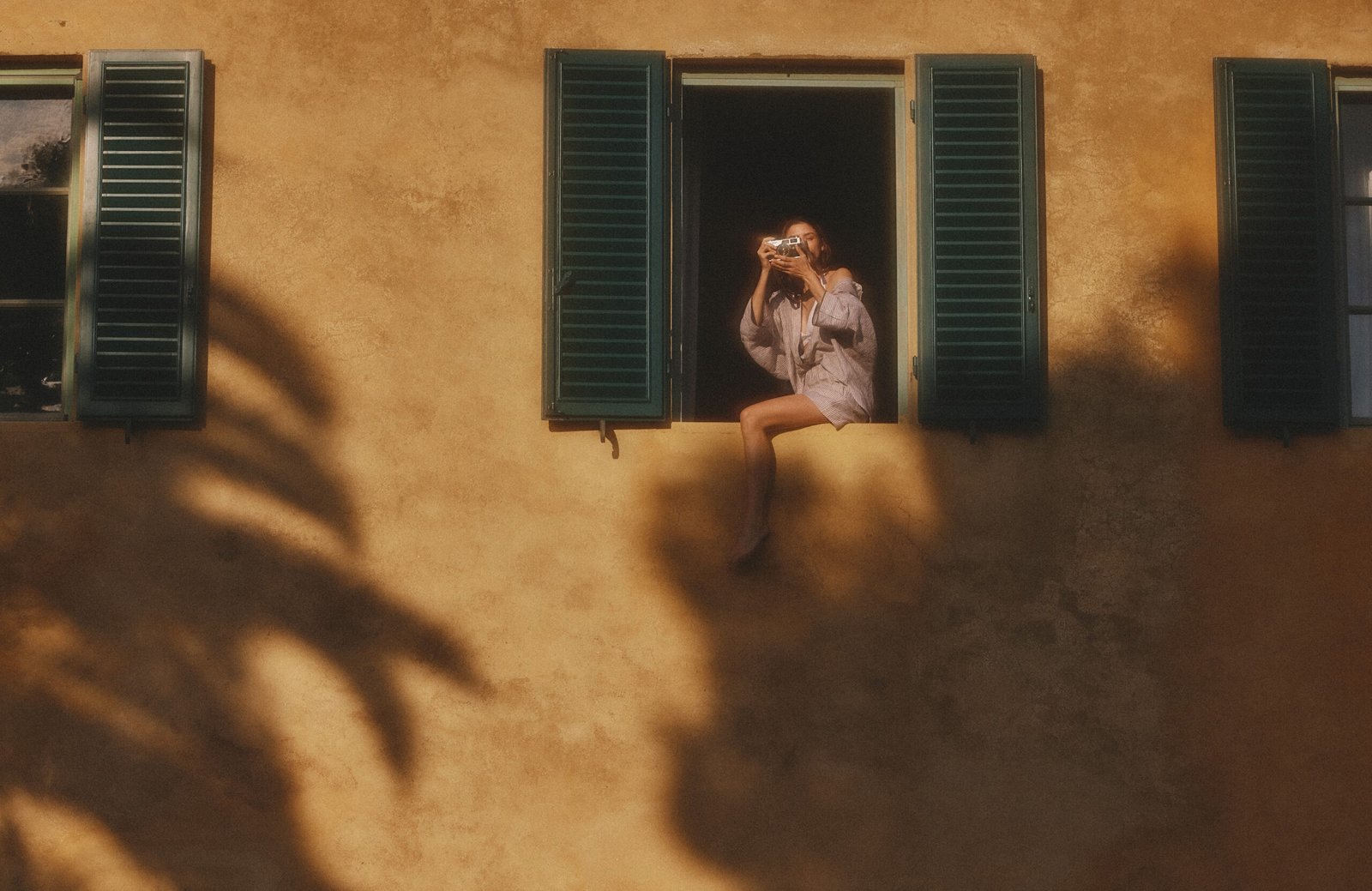 A women in window taking picture with camera