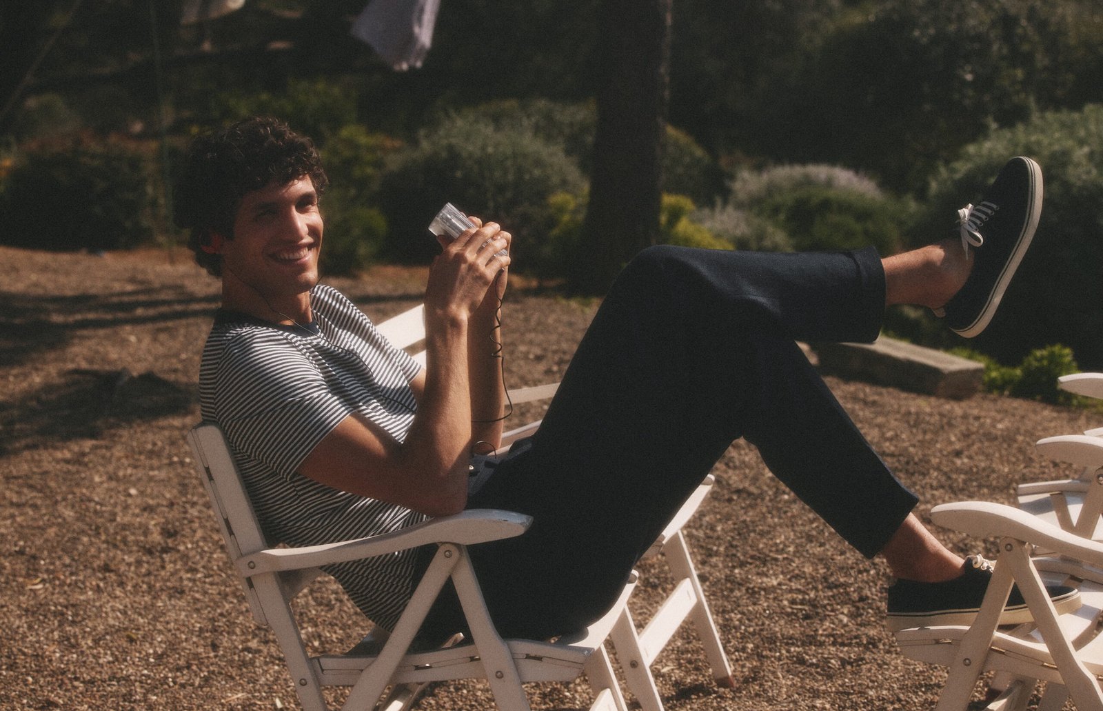 A man sitting on chair wearing stripped T-shirt and envy blue pants